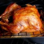 A simple roast turkey on a rack set over a roasting pan in the oven.