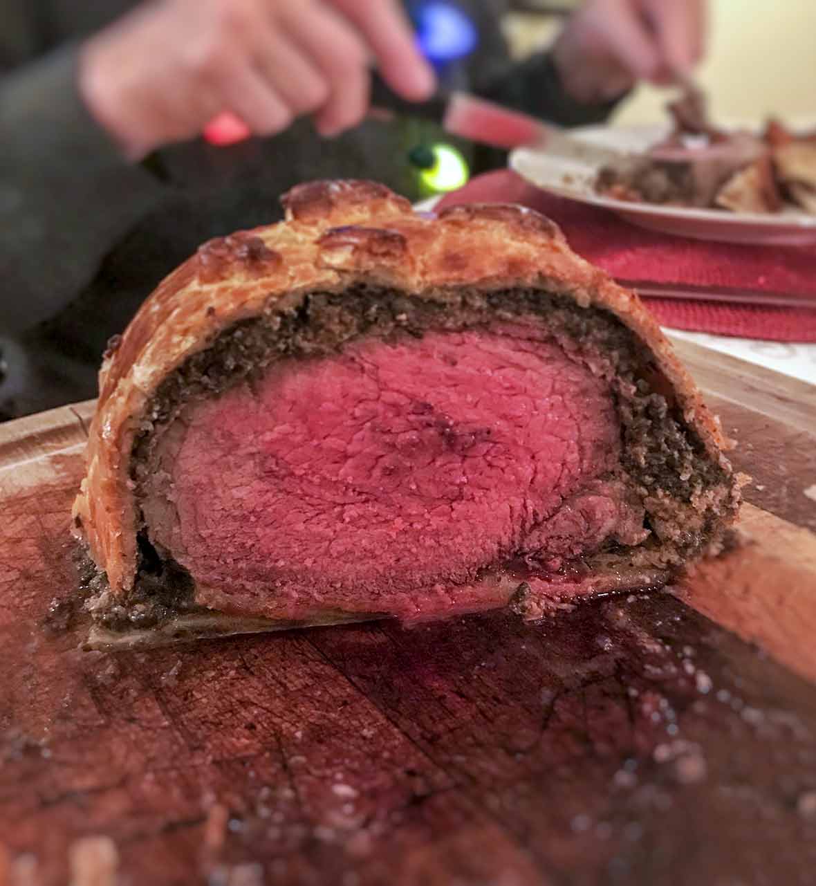 A beef tenderloin covered in pate and chopped mushrooms and wrapped in puff pastry on a cutting board