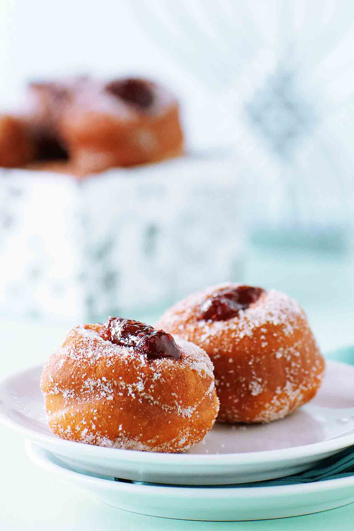 A white plate with two jelly-filled sufganiyot doughnuts.