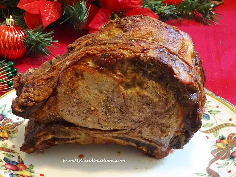 A full standing rib roast on a holiday plate atop a red tablecloth