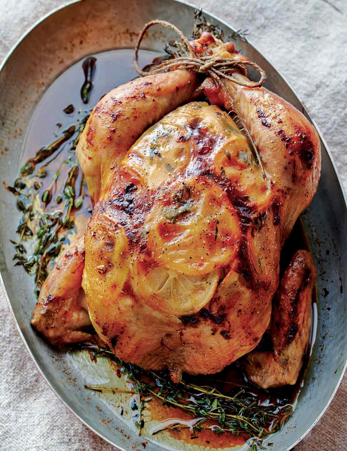 Roast chicken with lemon slices under the skin in a oval metal pan