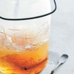 Glass jar with a cold and flu drink with a cinnamon stick, a spoon with ginger