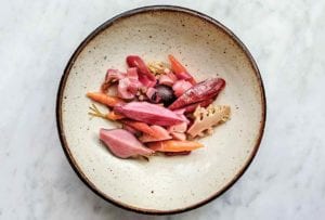 Plate of pickled carrots, beets, radishes, cauliflower, turnips on a marble slab