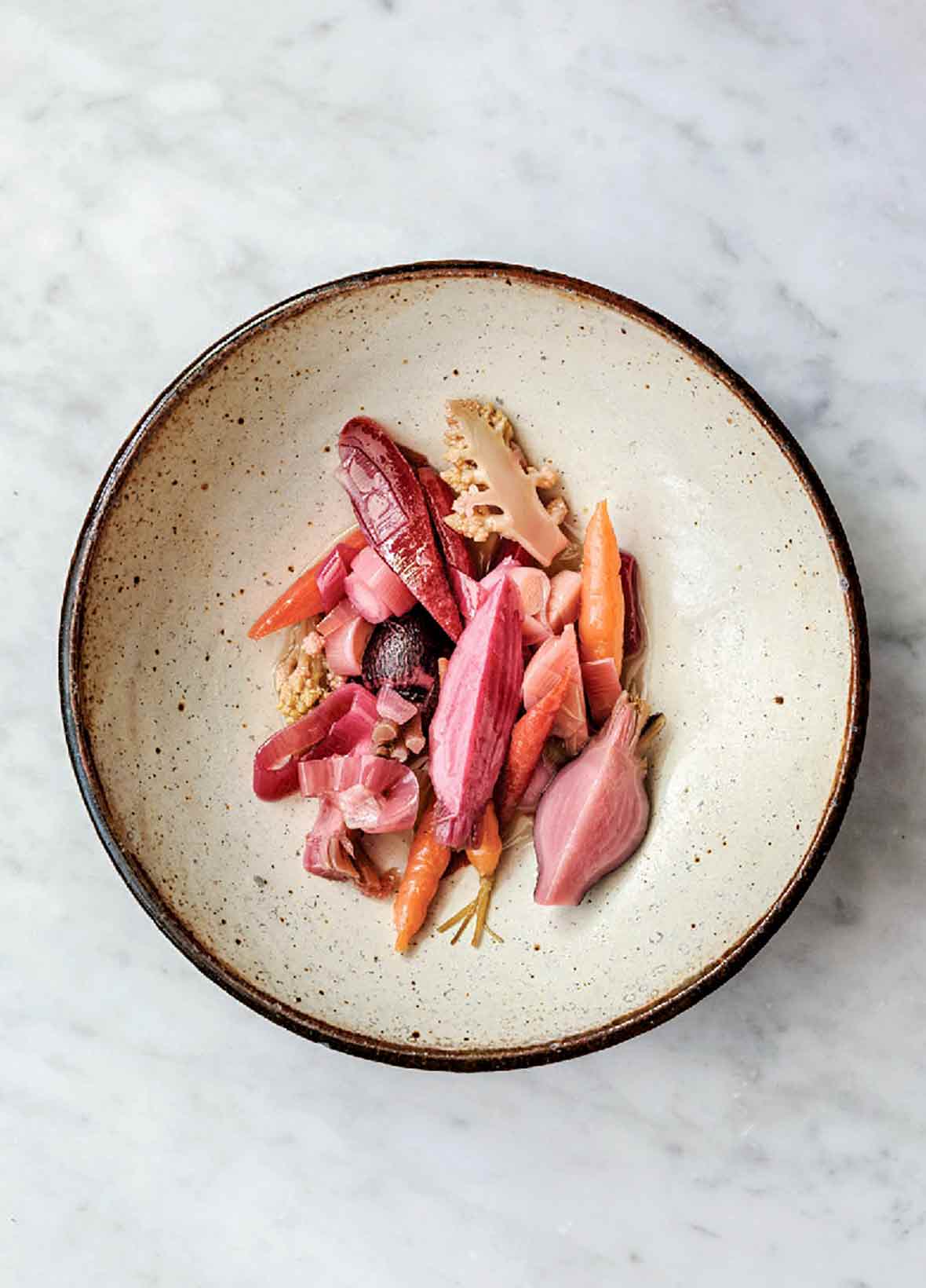 Plate of pickled carrots, beets, radishes, cauliflower, turnips on a marble slab