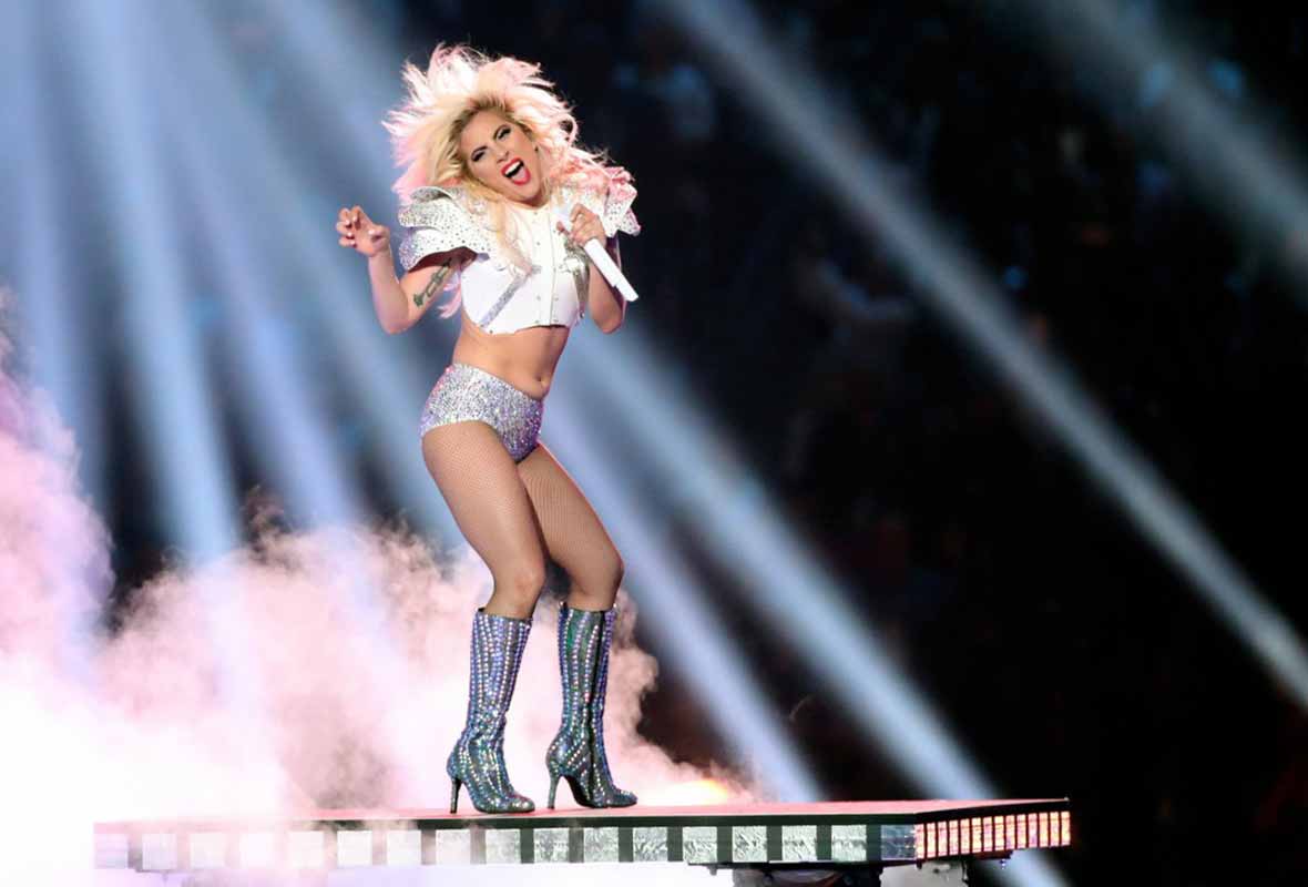 Lady Gaga is a bejeweled football outfit and high-heel boots singing