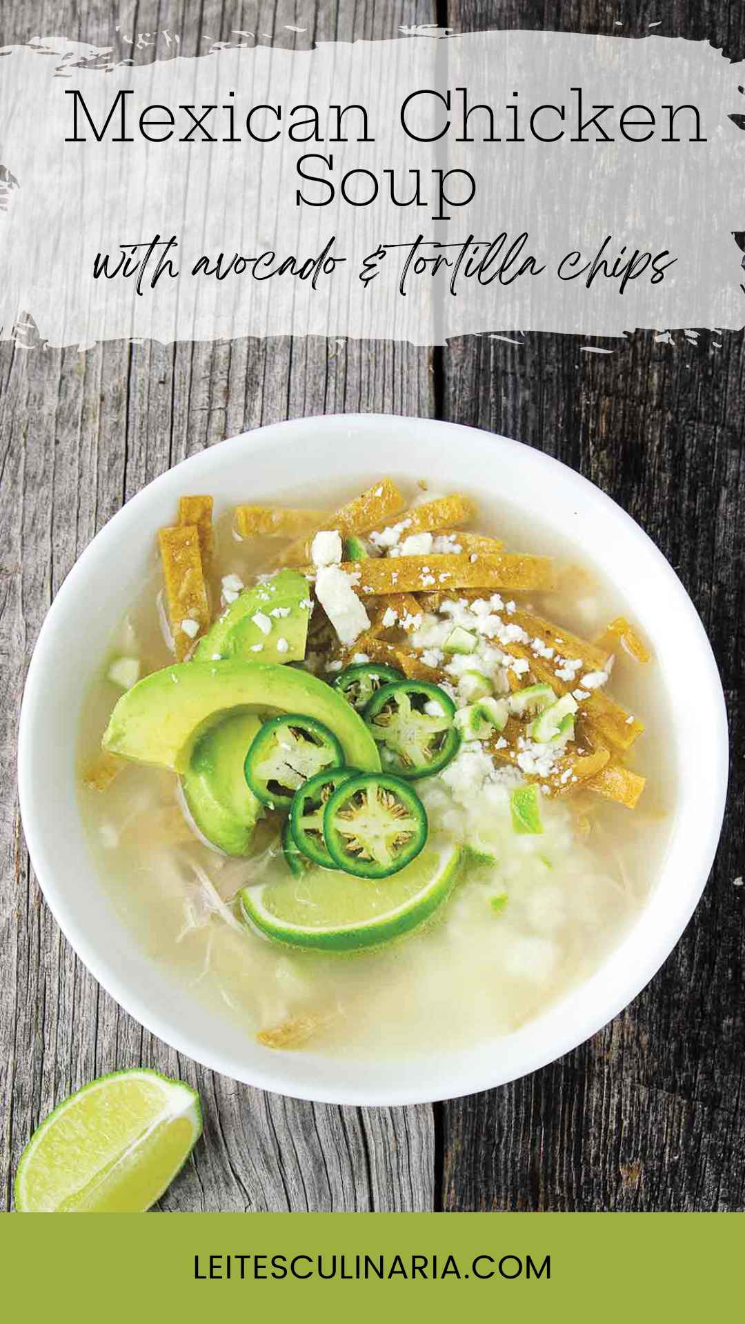 A white bowl filled with broth, avocado slices, lime wedges, cheese, and tortilla strips.