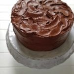 A Hershey chocolate cake with swirled chocolate frosting on a white cake stand