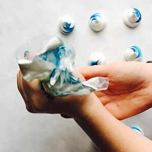 Hands piping blue and white meringues