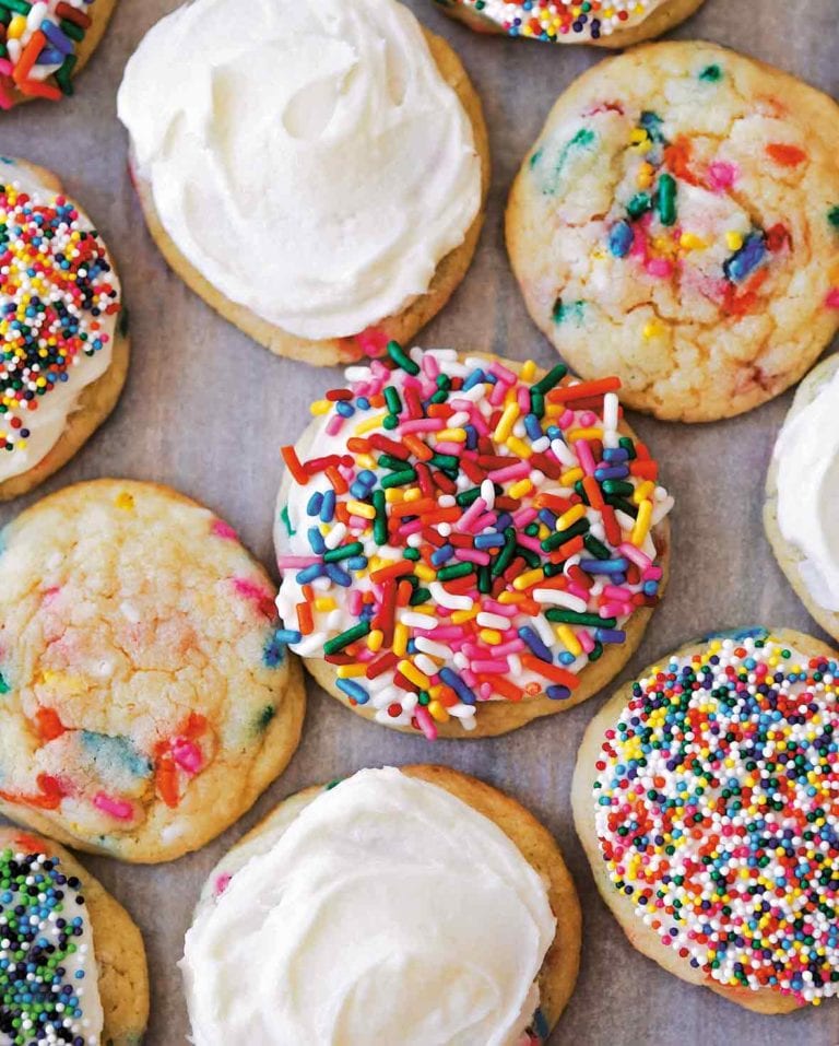 11 birthday cake cookies covered in white frosting and colored sprinkles
