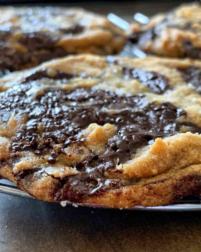 A close up shot of a few of David Leite's chocolate chip cookies on a wire cooling rack