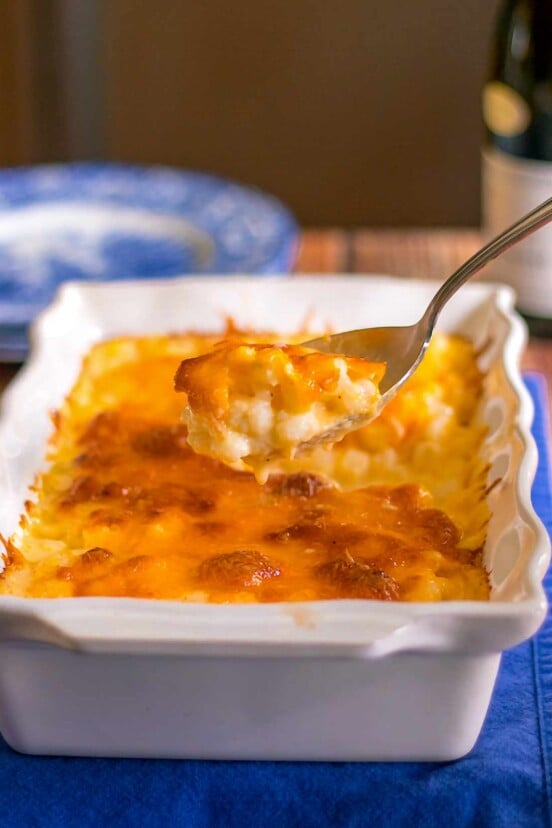 A casserole dish of hominy au gratin--hominy in a cheese sauce--plus a spoon filled with the cheesy hominy