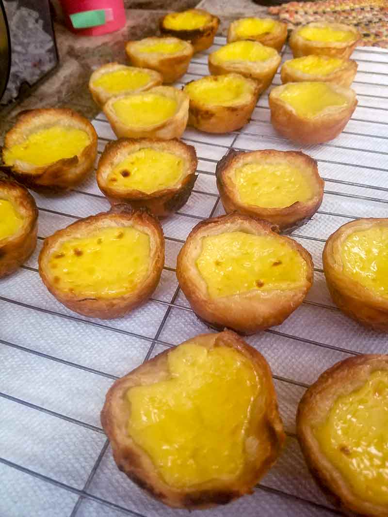 Portuguese custard pastries--crust shells filled with yellow custard--also called pasteis de nata on a wire rack