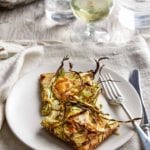 Plate with shaved asparagus pizza, fork and knife, on a kitchen towel