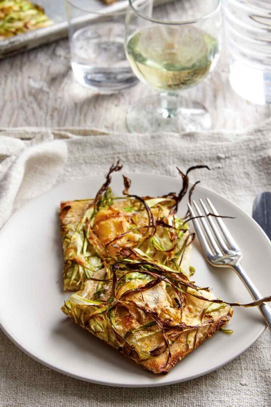 Plate with shaved asparagus pizza, fork and knife, on a kitchen towel