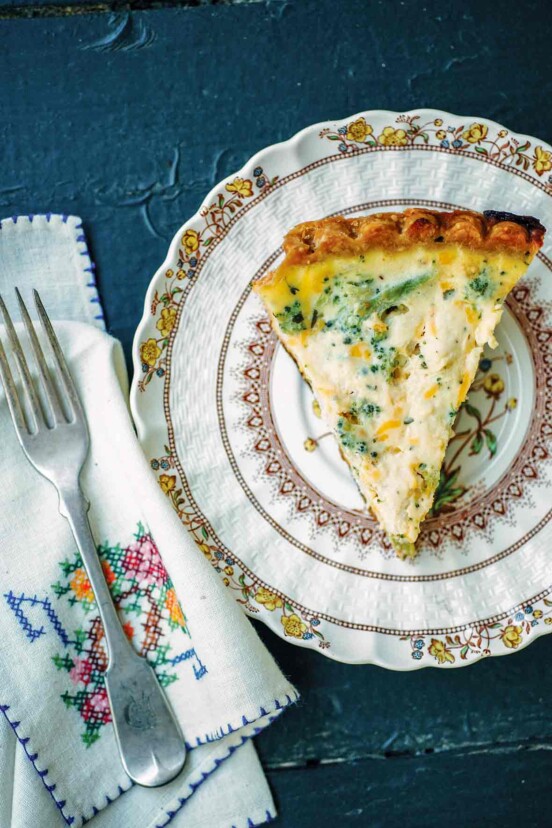 A plate with a slice of broccoli Cheddar quiche.