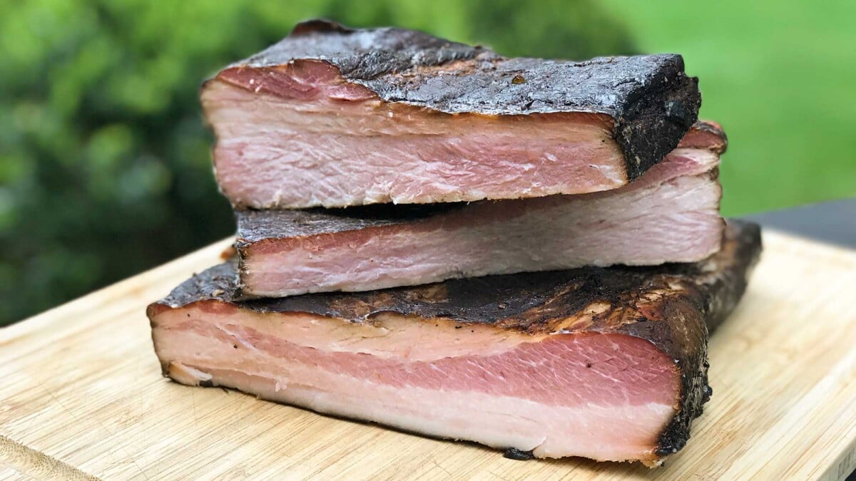 Three slabs of homemade maple espresso bacon on a cutting board