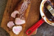 Cutting board with char siu pork--a pork tenderloin slathered with char siu sauce--and more sauce and the side