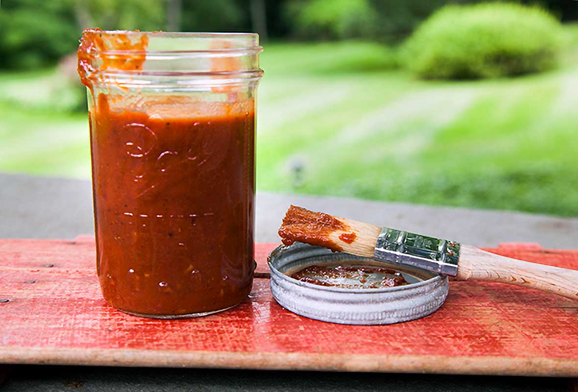 A basting brush and jar of with chipotle maple barbecue sauce