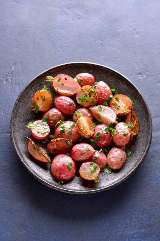 A grey bowl filled with roasted radishes, sprinkled with thyme.