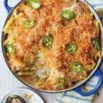 Blue casserole of spicy macaroni and cheese with breadcrumbs on top and sliced of jalapeno peppers.