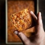 A man's hand holding a square of bacon cornbread