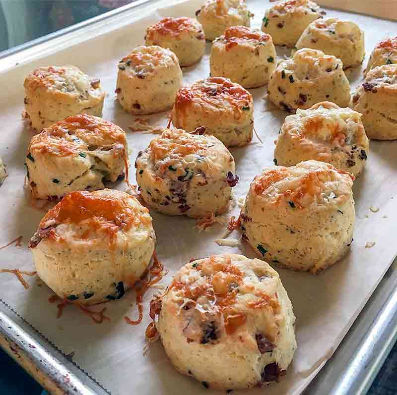 A baking sheet lined with parchment holding 17 bacon cheese biscuit bites