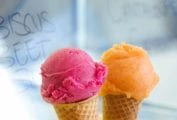 Two sugar cones, one filled with a scoop of cantaloupe sorbet, the other with a scoop of hibiscus sorbet.