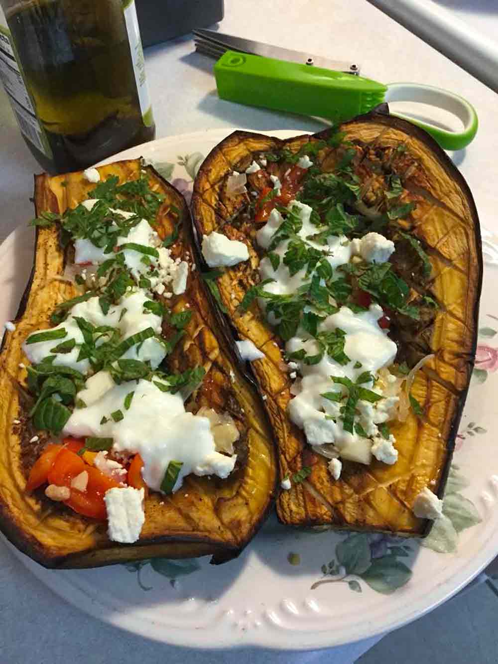 White and blue plate with Turkish baked eggplant topped with with chile, feta, and Mint