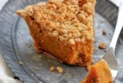 A wedge of bourbon sweet potato pie topped with a crumbly brown sugar streusel omn a metal plate