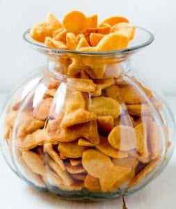 A glass jar filled to the brim with cheesy fish crackers.