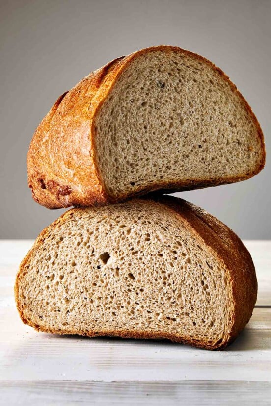 A loaf of Jewish rye bread, cur in half, one half balancing on the other
