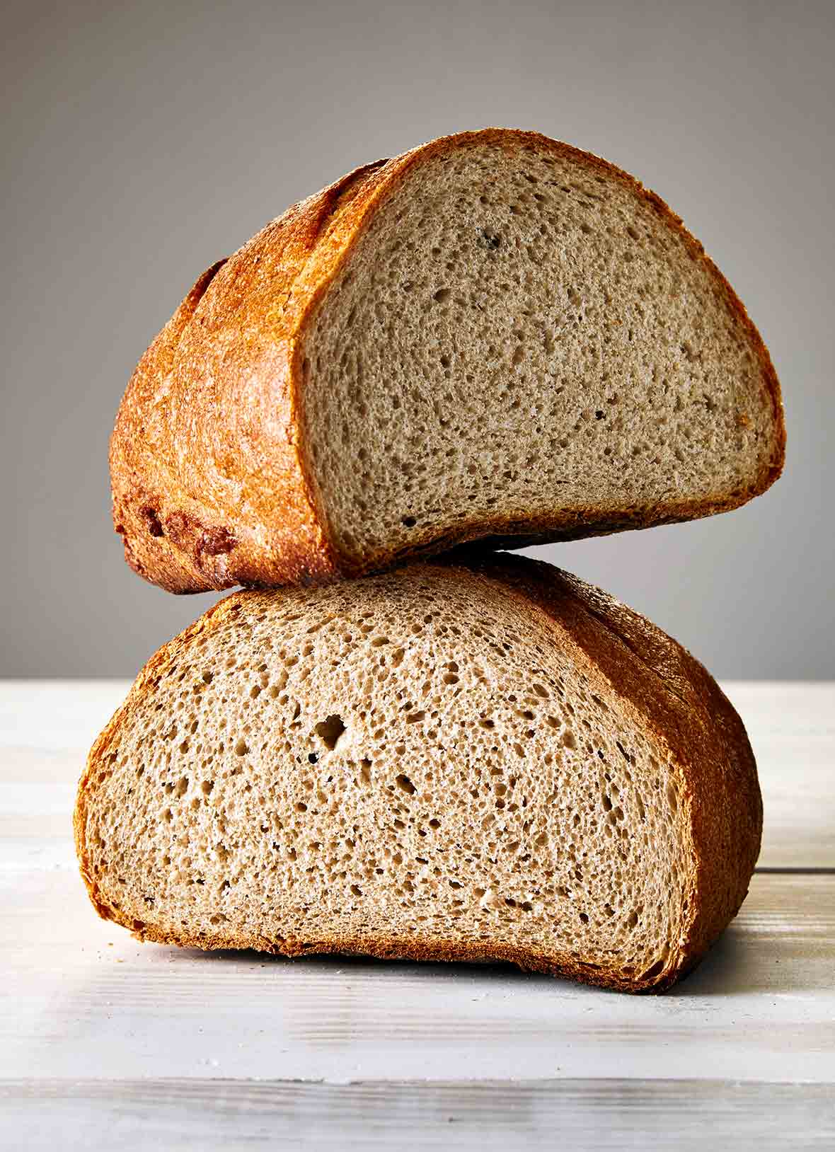 A loaf of Jewish rye bread, cur in half, one half balancing on the other