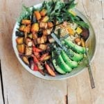 A bowl of miso-glazed kabocha squash with carrots, avocado, salad greens, seaweed over brown rice.