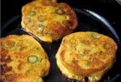 Three okra cornmeal cakes--with rings of green okra in it--in a black cast iron skillet