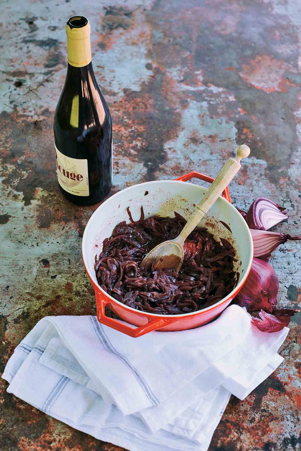 A red Le Creuset pot filled with red wine onions, that have been slowly cooked together