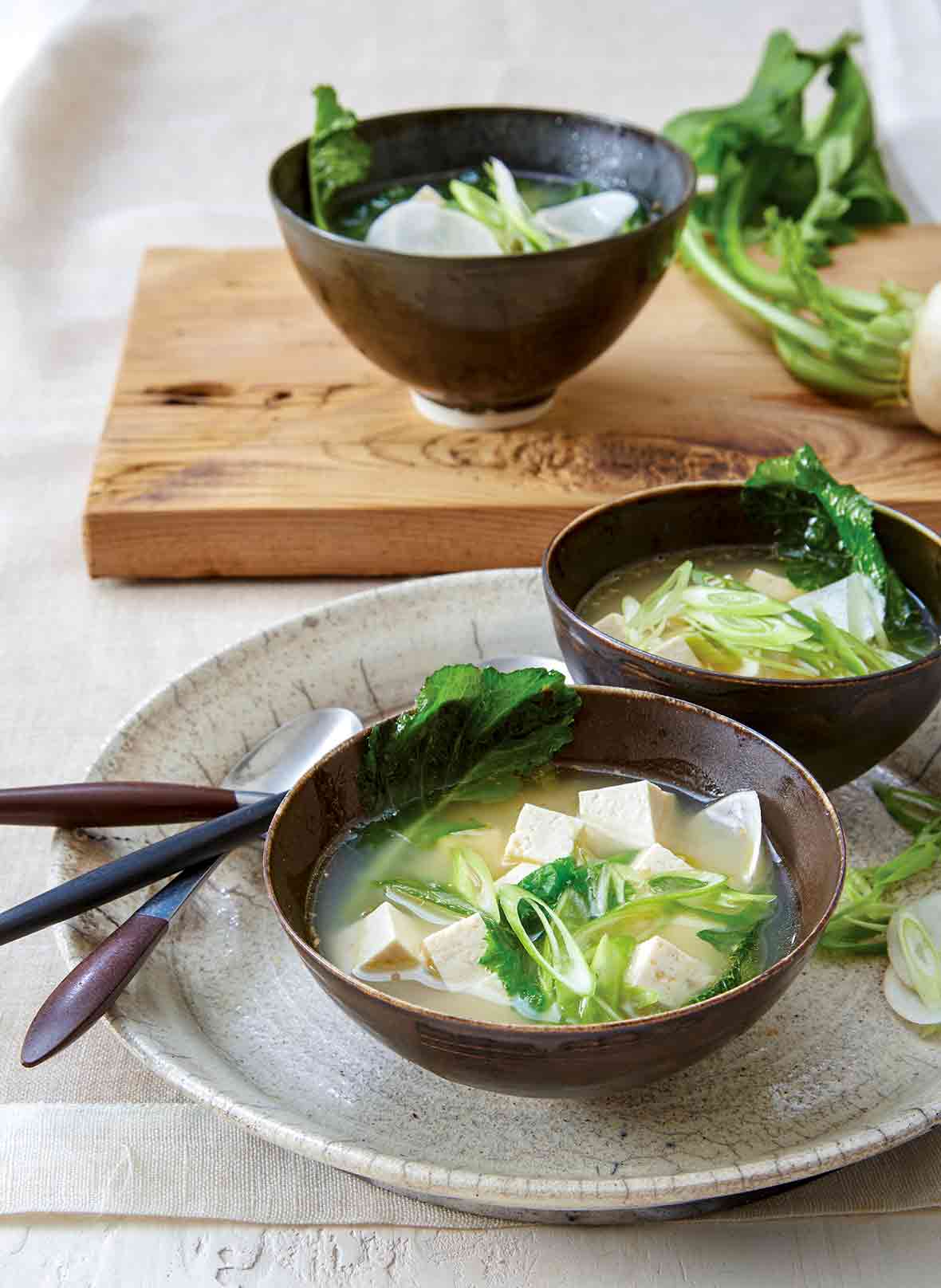 Two bowls of ginger miso soup with tofu, turnip greens, and miso broth