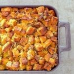 Casserole dish of cubes of homemade cornbread sausage dressing, with pork sausage, onion, celery, and spices