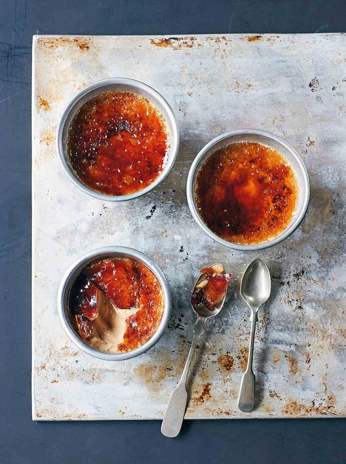 Tre ramekins fyllda med masala chai creme brûlée, en med toppen sprucken upp för att avslöja den krämiga insidan