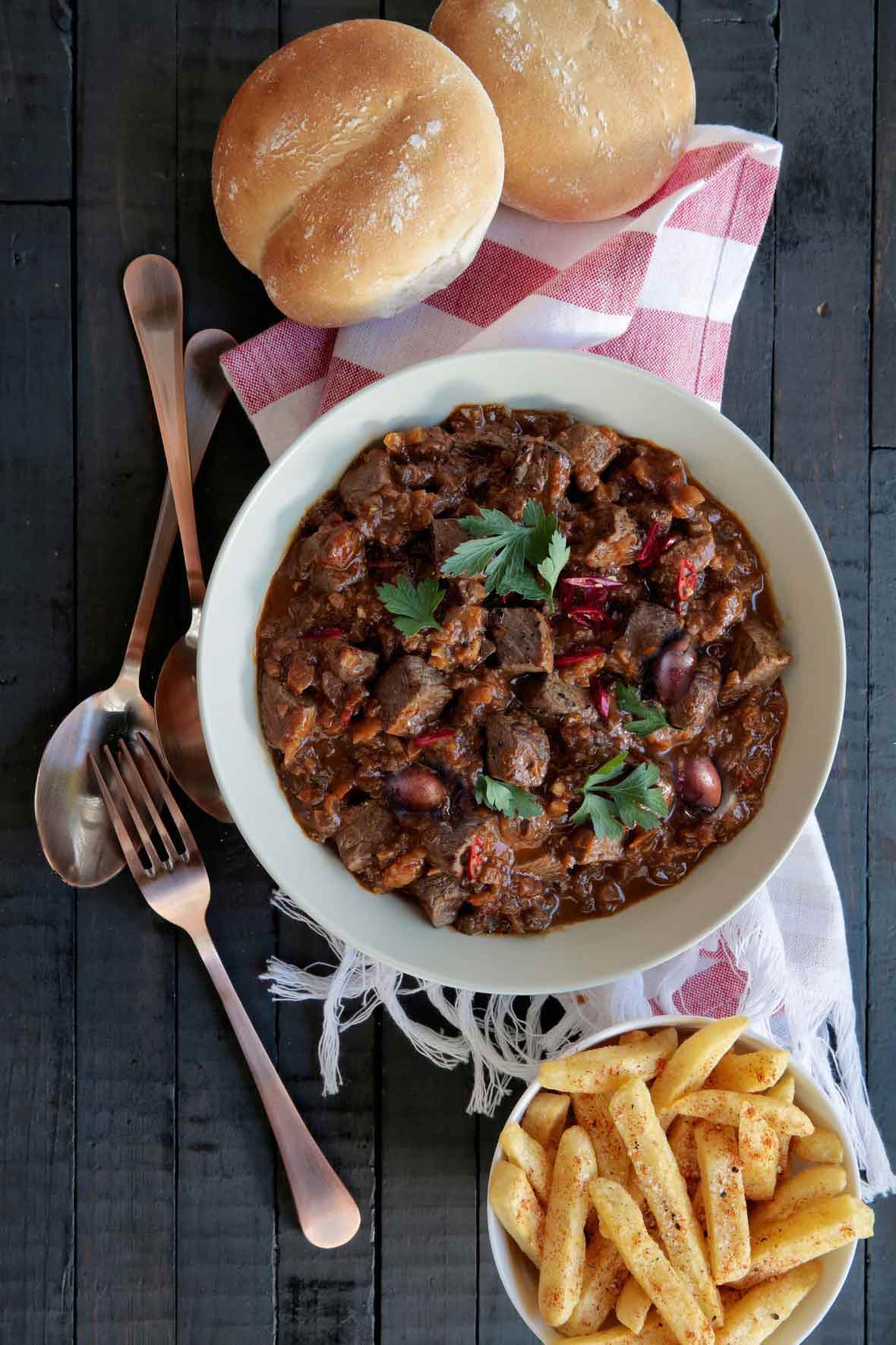 A bowl of trinchado, or chunks of spicy South African braised beef, served with french fries and Portuguese rolls--papos secos