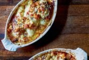 Two oval gratin dishes filled with braised endive gratin topped with bubbly browned cheese and breadcrumbs