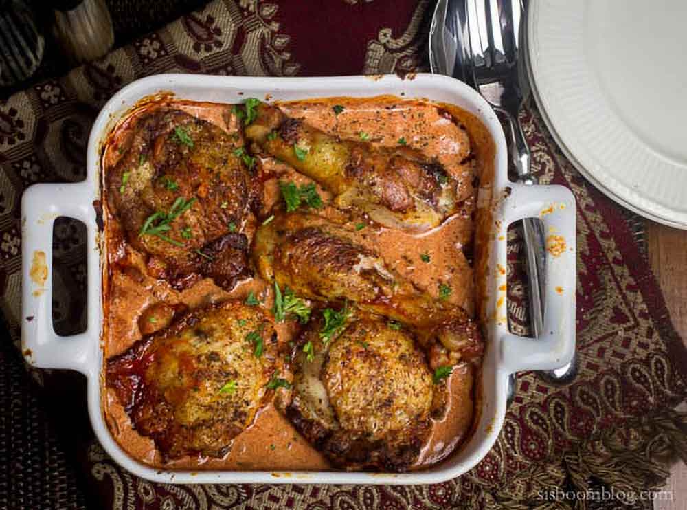 A white square casserole dish of chicken paprikash chicken legs and thighs in a sour cream paprika sauce
