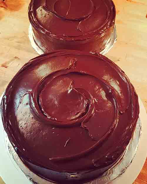 A counter with two double layer Hershey chocolate cakes frosted with Hershey chocolate frosting