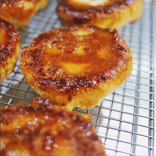 Five koiugn amman--puff pastry coated with sugar--on a wire rack