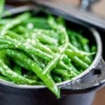 A cast-iron pot filled with pan-fried green beans tossed with garlic and butter