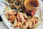 White and blue plate with sliced roast turkey breast with herbed stuffing and gravy.