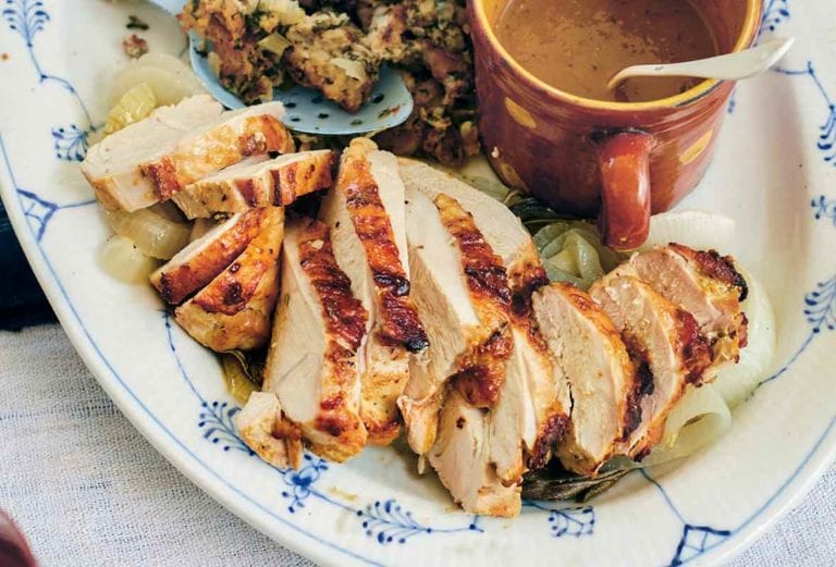 White and blue plate with sliced roast turkey breast with herbed stuffing and gravy