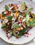 A plate of roasted delicata squash salad with red onion, feta cheese, avocado, and mint.