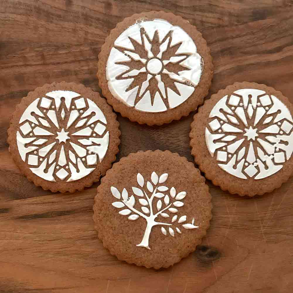 Four Swedish black pepper cookies called pepperkakor decorated with snowflake and tree icing designs