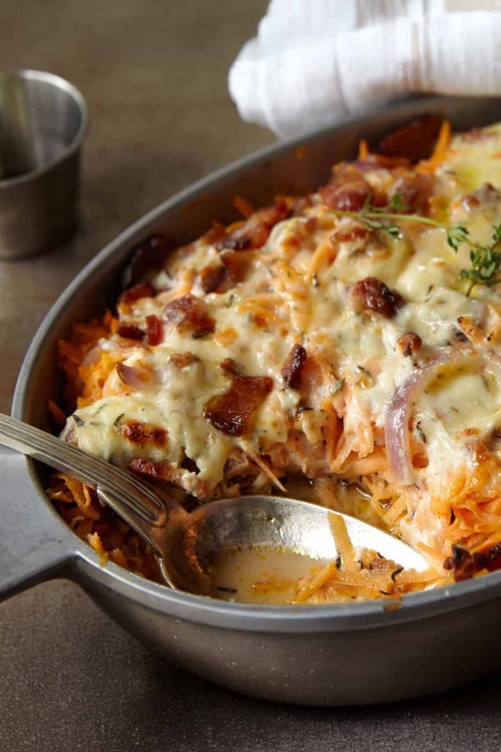 A chicken, sweet potato, and bacon casserole in an oval dish, topped with melted cheese.