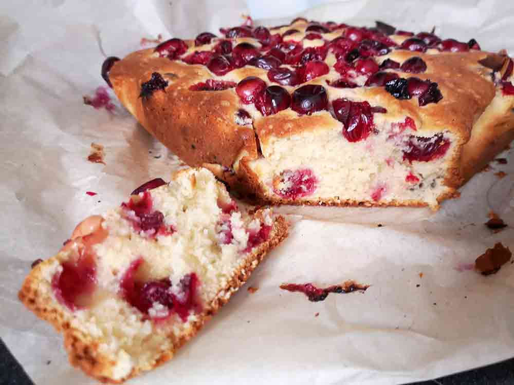 A cranberry buckle that has been cut up; topped with cranberries